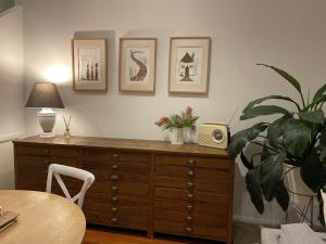 une pièce avec une commode en bois, une table et une plante dans l'établissement River Retreat, à Grays Point