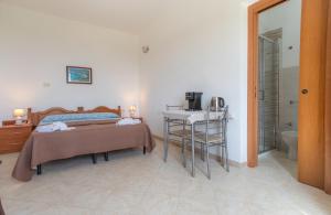 a bedroom with a bed and a table and a bathroom at Dammuso Ignazio in Lampedusa