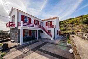 une maison blanche avec des fenêtres rouges et un escalier dans l'établissement Adega Pedra do Lagar, à Calheta de Nesquim