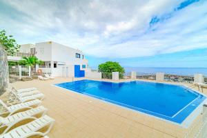 a swimming pool with chairs and a building at Stunning cliffs and ocean view in Los Gigantes in Acantilado de los Gigantes