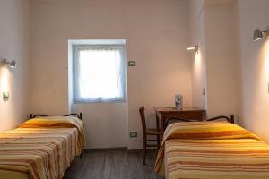 two beds in a room with a table and a window at Appartamenti Nadalini in Levico Terme