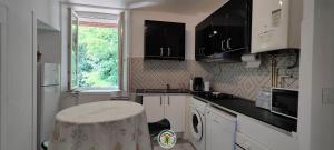 a kitchen with white cabinets and a table in it at Le Paviot in Voiron