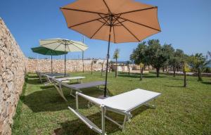 a group of picnic tables with an umbrella at Dammuso Ignazio in Lampedusa