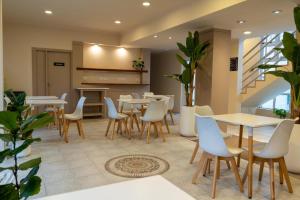 a restaurant with white tables and chairs and plants at Hotel PUERTO A in Gualeguaychú