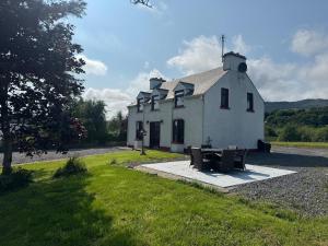 a white building with a picnic table in front of it at Modern Coastal Cottage in Killybegs