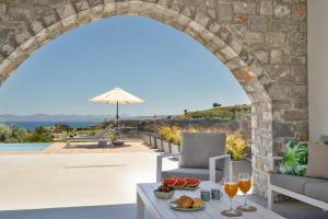 an archway over a patio with a table with wine glasses at Villa Meraki in Stalos