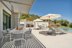 a patio with a table and chairs and an umbrella at Villa Meraki in Stalos