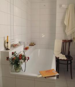 a white bathroom with a tub with a vase of flowers at Casa Vacanze Parco San Bartolo in Pesaro