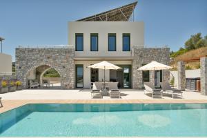 a villa with a swimming pool with chairs and umbrellas at Villa Meraki in Stalos