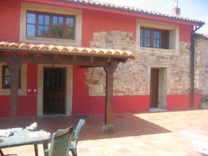 einen Tisch und Stühle vor einem roten Gebäude in der Unterkunft La Busta in Villaviciosa