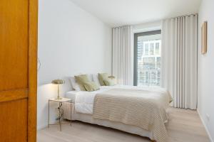 a white bedroom with a bed and a window at Central Heaven in Ostend +33 photos