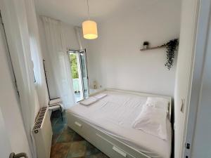 een witte slaapkamer met een bed en een raam bij Mountain View Apartment Lefkada in Apolpaina