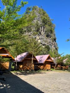 a group of buildings with a mountain in the background at Cottage Pier 2 of Rammang-Rammang in Kasijala