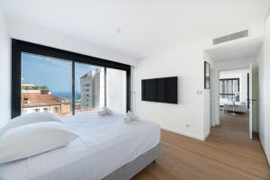 a bedroom with a large white bed and a large window at Luxury 3BR Apartment with Sea View in Beausoleil