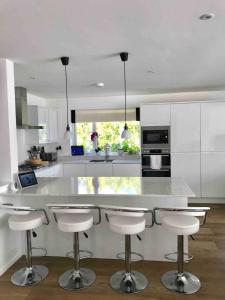 a kitchen with a large white counter with bar stools at Featured on Channel 4 with George Clarke with lazy spa in Bournemouth