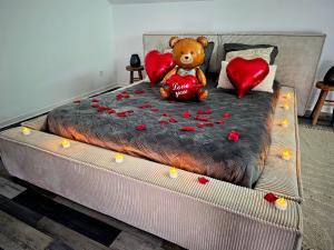 a teddy bear sitting on a bed with red hearts at Love Room Luxe and Spa - Sauna in Domérat