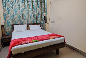 a bedroom with a bed with a red blanket at Hotel Shiva in Navi Mumbai