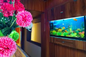 a vase of pink flowers and a fish tank at Hotel Shiva in Navi Mumbai