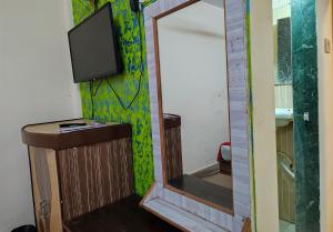 a bathroom with a mirror and a tv on a wall at Hotel Shiva in Navi Mumbai +5 photos