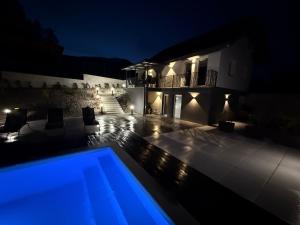 a swimming pool in front of a house at night at PJ Resort - Pool & Mountain View in Cerklje na Gorenjskem