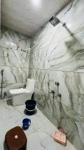 a white bathroom with a toilet and a sink at Hotel Sindur in Ujjain