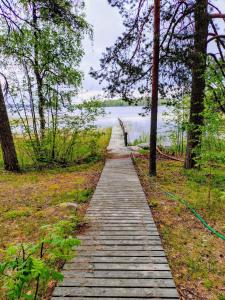un sentiero in legno attraverso una foresta vicino a un corpo d'acqua di Ylisen Kartano a Kaihari