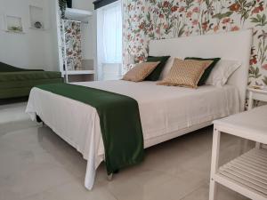 a bedroom with a white bed with a green blanket on it at DOMUS ULIVI LUXURY ROOMS Nocellara in Catania +21 photos