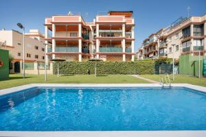 un apartamento con piscina frente a un edificio en Camaleón 7, en Chipiona