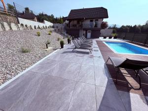 a patio with lounge chairs and a swimming pool at PJ Resort - Pool & Mountain View in Cerklje na Gorenjskem
