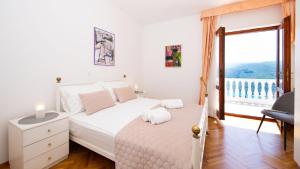 a white bedroom with a bed and a window at La casa di Marko Sea View Apartments in Rabac