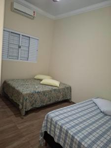 a bedroom with two beds and a window at Casa Alice e Matheus in Olímpia +17 photos