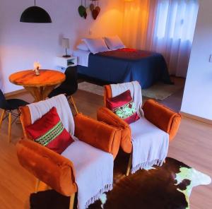a bedroom with two chairs and a bed and a table at Angatu chalé in Gonçalves