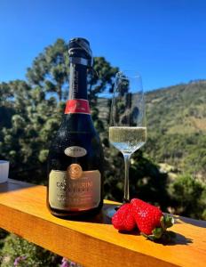 a bottle of wine next to a glass and strawberries at Angatu chalé in Gonçalves