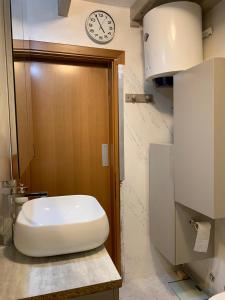 a bathroom with a toilet and a clock on the wall at Bouganville in Villanovafranca