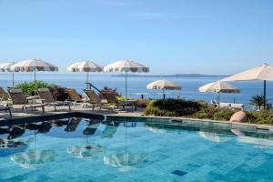 a swimming pool with chairs and umbrellas at Hôtel La Villa Douce in Rayol-Canadel-sur-Mer