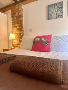 ein Schlafzimmer mit einem Bett mit zwei Eulenkissen darauf in der Unterkunft Otters Holt at Tove Valley Cottages in Towcester + 4 Fotos