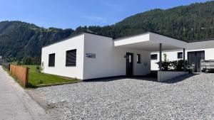 a white building with a gravel driveway at Bungalow Laroo in Ried im Oberinntal