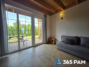 a living room with a couch and a large sliding glass door at 365PAM - Urocze Domki Letniskowe blisko morza in Bobolin +17 photos