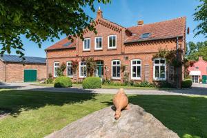 a cat statue sitting on a rock in front of a house at Ferienwohnung Bauernhof Rohde in Gremersdorf