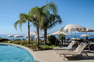 a swimming pool with chairs and umbrellas at Hôtel La Villa Douce in Rayol-Canadel-sur-Mer