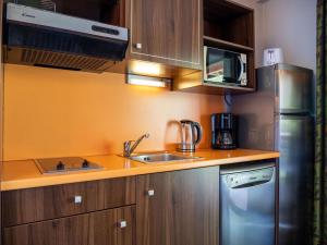 a kitchen with wooden cabinets and a stainless steel refrigerator at Charmant T2 dans un château à Jausiers, piscine et sauna, idéal pour 4 personnes - FR-1-165B-42 in Jausiers