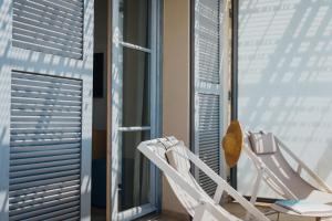 a couple of white chairs sitting in front of a window at Hôtel La Villa Douce in Rayol-Canadel-sur-Mer