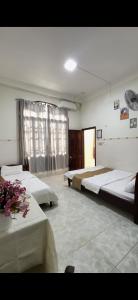 a room with three beds and a table with flowers at Hotel Ngọc My in Phan Thiet +2 photos