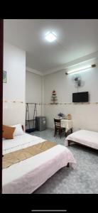 a bedroom with two beds and a table with a television at Hotel Ngọc My in Phan Thiet
