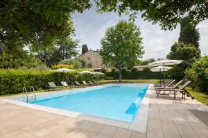 a pool with chairs and umbrellas next to a house at Il Belcanto Villa with Pool in Cavaion Veronese
