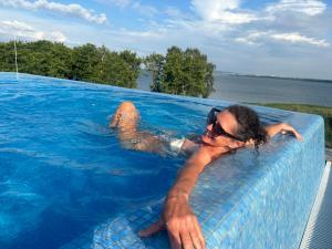 Apartament Sea & Lake z basenem Silence Mielno في ميلنو: رجل مستلقٍ على حوض سباحة في الماء