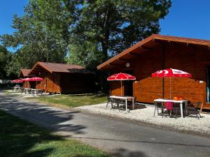 grupa stołów z parasolami przed budynkiem w obiekcie Camping les 2 salamandres w mieście Arces-sur-Gironde