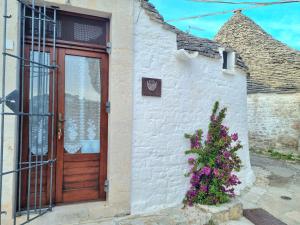 a house with a wooden door and a bush with purple flowers at Romantic Corner in Alberobello