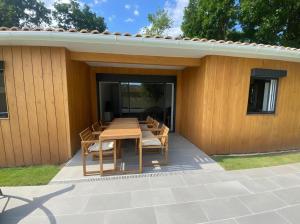 a patio with a wooden table and chairs at maison Lège cozy in Lège-Cap-Ferret