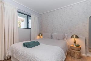 a bedroom with a white bed with a green towel on it at Modern One Bedroom Wavescapes Apartment Muizenberg in Muizenberg